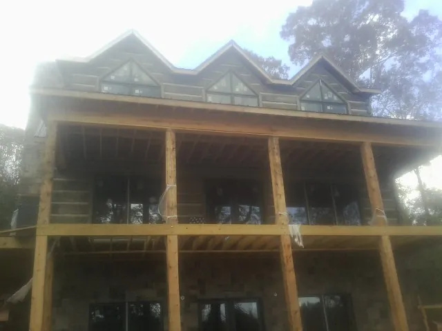 Dormers and porch framing on a large log home under construction — Roof Coating work by our crew in Center Ossipee