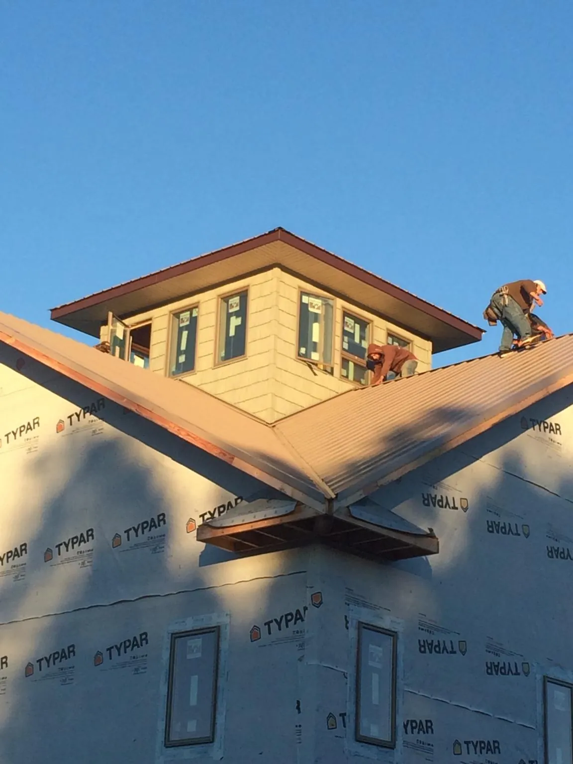 Roofers working around a rooftop cupola on a new metal roof at sunset — Roof Waterproofing in Center Ossipee by Roofing Brothers